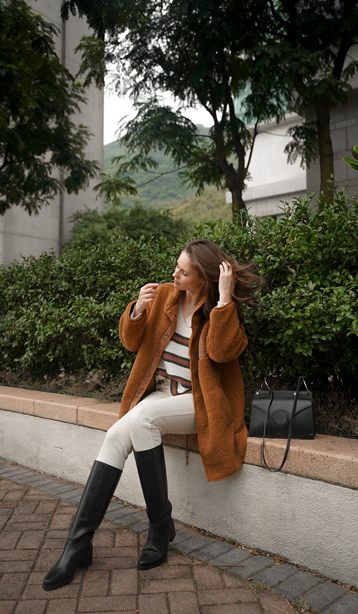 Alyssa Campanella of The A List blog shares her daily looks wearing Legres riding boots, Khaite Vanessa jeans, Aerie dreamspun sweater, Aerie sherpa jacket, and Danse Lente Phoebe bag